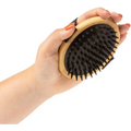 Hand holding Mikki Bamboo Moulting Massage Palm Brush with black bristles for grooming